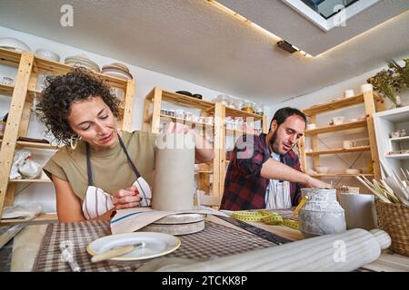 Zwei Töpfer konzentrierten sich intensiv auf die Gestaltung und Detaillierung ihrer Keramikstücke und tauchten in den kreativen Fluss ihres Handwerks ein. Handwerkskunst Stockfoto