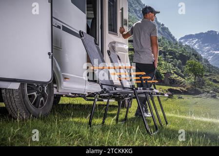 Urlaub in einem Freizeitfahrzeug. Besitzer eines kaukasischen Wohnmobils vor seinem Fahrzeug. Stockfoto