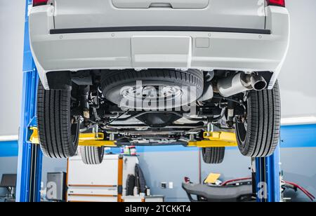 Thema Automobilindustrie. Modernes Auto auf einem Aufzug im Auto Service Shop. Ansicht Von Hinten Von Unten. Stockfoto