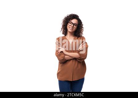 Junge lockige Brünette Geschäftsfrau in braunem Hemd und Jeans Stockfoto