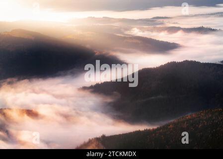 Berge in niedrigem dichtem Nebel am Morgen Sonnenaufgang. Wunderschöne Landschaft mit Berggipfeln im Nebel. Bergtal in Wolken. Stockfoto
