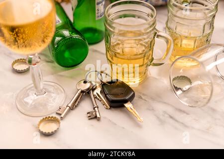 Ein Satz Autoschlüssel auf einem Tisch voller Gläser mit alkoholischen Getränken und Flaschen. Getränk Fahrkonzept. Stockfoto