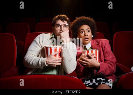 Erstaunt schockiert verschiedene Paare in stylischen Retro-Kleidern, die sich Filme im Kino ansehen, Valentinstag Stockfoto