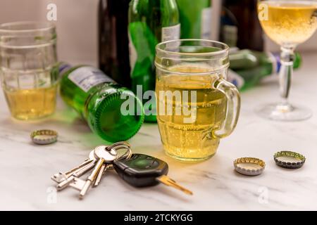 Ein Satz Autoschlüssel auf einem Tisch voller Gläser mit alkoholischen Getränken und Flaschen. Getränk Fahrkonzept. Stockfoto