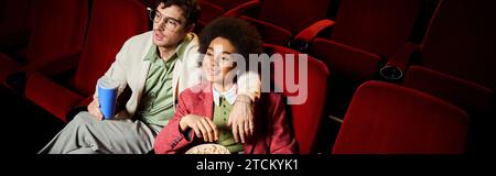 Attraktives, abwechslungsreiches Paar in stilvollen Kleidern, das Filme im Kino, Valentinstag, Banner ansieht Stockfoto