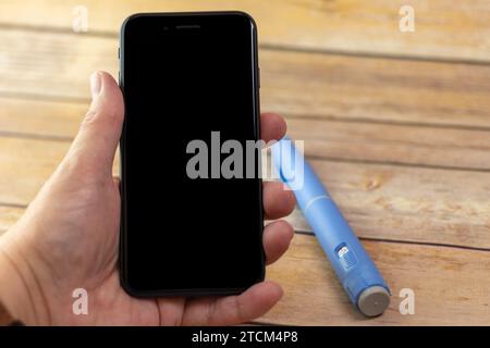 Ein mobiles Handgerät mit Semaglutid-Stift im Hintergrund Stockfoto