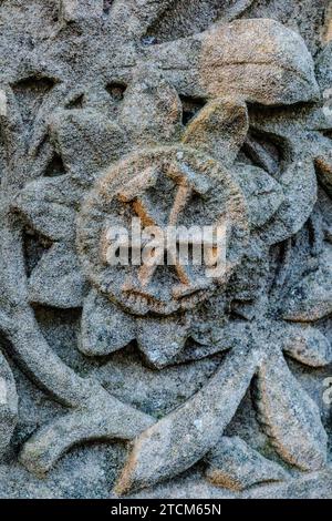 Nahaufnahme von Schnitzereien auf Grabstein. Gekreuzte Hämmer in Blütenform. Alt. Sandstein mit Körnung. Stockfoto