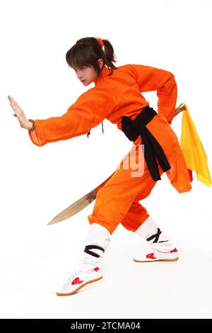 Wushu-Mädchen in Orange machen Übung von Shaolin Taolu Stockfoto