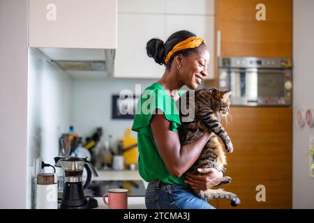 Lächelnde Frau, die ihre Katze zu Hause hält Stockfoto
