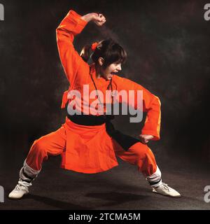 Wushu-Mädchen in Orange machen Übung von Shaolin Taolu Stockfoto