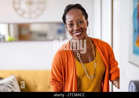Porträt einer lächelnden Reifen Frau, die in ihrer Wohnung steht Stockfoto