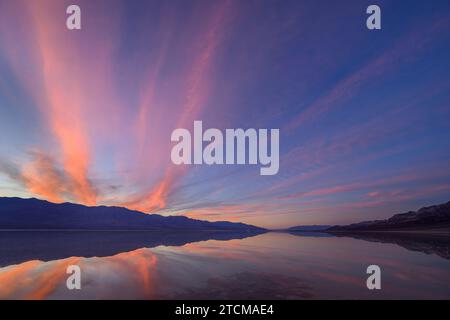 Sonnenuntergang über den Panamint Mountains mit überflutetem Badwater Basin, der Lake Manly nachbildet; Death Valley National Park, Kalifornien. Stockfoto