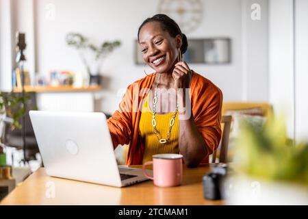 Lächelnde Frau am Laptop zu Hause arbeiten Stockfoto
