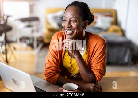 Lächelnde Frau am Laptop zu Hause arbeiten Stockfoto