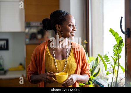 Porträt einer lächelnden Reifen Frau, die in ihrer Wohnung steht Stockfoto