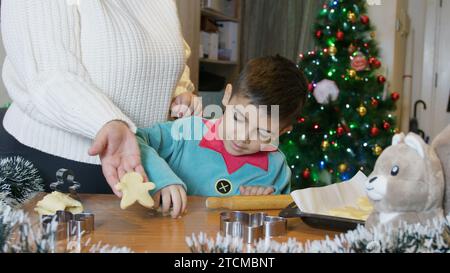 Weihnachtszeit mit der Familie. Mom und Sohn machen Lebkuchen-Mann-Kekse. Mom hält Kekse zum Backen bereit. Hochwertige Fotos Stockfoto