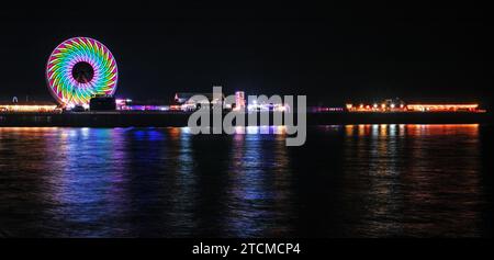 Ein Panoramablick auf den zentralen Pier von Blackpool, mit den Lichtern, die sich im Wasser spiegeln Stockfoto