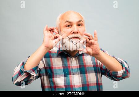 Friseur Senior mit Friseurschere. Mann mittleren Alters. Porträt eines alten kahlen Mannes bärtiger Mann mit grauem Schnurrbart. Stockfoto