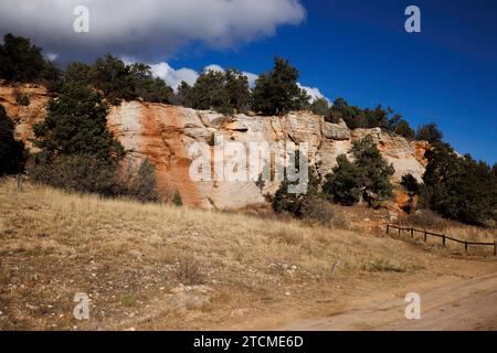 Feldweg vorbei an roten und weißen Felsen mit Zaun Stockfoto