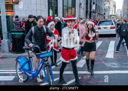 Hunderte von Santas, begleitet von ihren Helfern und einigen frechen Elfen, warten online, um die Smith Bar im Nomad-Viertel in Manhattan in New York während des jährlichen Kneipenbummels SantaCon am Samstag, den 19. Dezember 2023, zu betreten. Die SantaCon, in erster Linie ein Kneipenbummel in Weihnachtskostümen und anderen Weihnachtskostümen, zieht Maskierer an, die von Bar zu Bar gehen. (© Richard B. Levine) Stockfoto