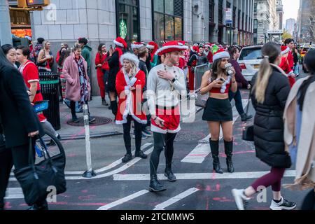 Hunderte von Santas, begleitet von ihren Helfern und einigen frechen Elfen, warten online, um die Smith Bar im Nomad-Viertel in Manhattan in New York während des jährlichen Kneipenbummels SantaCon am Samstag, den 19. Dezember 2023, zu betreten. Die SantaCon, in erster Linie ein Kneipenbummel in Weihnachtskostümen und anderen Weihnachtskostümen, zieht Maskierer an, die von Bar zu Bar gehen. (© Richard B. Levine) Stockfoto