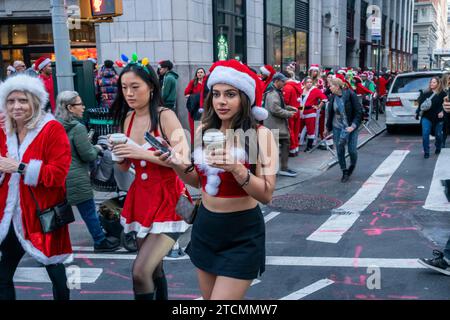 Hunderte von Santas, begleitet von ihren Helfern und einigen frechen Elfen, warten online, um die Smith Bar im Nomad-Viertel in Manhattan in New York während des jährlichen Kneipenbummels SantaCon am Samstag, den 19. Dezember 2023, zu betreten. Die SantaCon, in erster Linie ein Kneipenbummel in Weihnachtskostümen und anderen Weihnachtskostümen, zieht Maskierer an, die von Bar zu Bar gehen. (© Richard B. Levine) Stockfoto