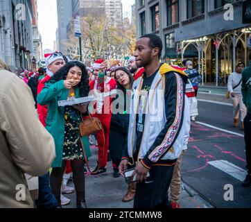 Hunderte von Santas, begleitet von ihren Helfern und einigen frechen Elfen, warten online, um die Smith Bar im Nomad-Viertel in Manhattan in New York während des jährlichen Kneipenbummels SantaCon am Samstag, den 19. Dezember 2023, zu betreten. Die SantaCon, in erster Linie ein Kneipenbummel in Weihnachtskostümen und anderen Weihnachtskostümen, zieht Maskierer an, die von Bar zu Bar gehen. (© Richard B. Levine) Stockfoto