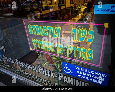 Ein Schild am Fenster eines Restaurants in Midtown Manhattan in New York informiert die Kunden darüber, dass es streng koscher ist, sowohl auf Englisch als auch auf Hebräisch, zu sehen am Sonntag, 10. Dezember 2023. (© Richard B. Levine) Stockfoto