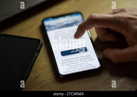 Klicken Sie auf die Schaltfläche „Hochladen“ in der Smartphone-App Stockfoto