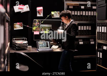 Polizist untersucht Betrugsfälle, analysiert vertraulichen Bericht, arbeitet spät in der Nacht im fbi-Arhive-Raum. Privatdetektiv entdeckt Kriminalbeweise, Planungsstrategie, um Verdächtige zu fangen. Stockfoto