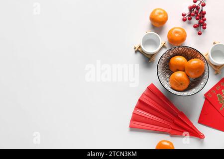 Mandarinen mit Umschlägen, japanischem Ventilator und Teetassen auf weißem Hintergrund. Neujahrsfeier Stockfoto