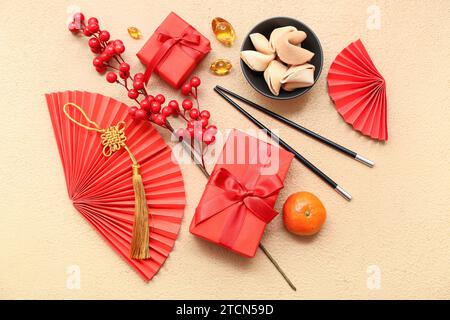 Geschenkbox mit Glückskeksen, Essstäbchen und chinesischen Symbolen auf beigefarbenem Hintergrund. Neujahrsfeier Stockfoto