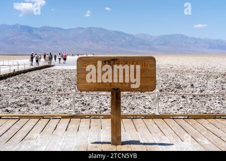 Badwater Basin-Schild mit unbekannten Besuchern im Hintergrund im Death Valley NP, Kalifornien, USA Stockfoto