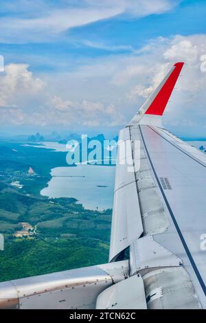 Der Flügel eines Flugzeugs fliegt über Krabi, Phang Nga Bay und die Inseln der Andamanensee auf dem Weg nach Phuket an einem sonnigen, aber trüben Tag Stockfoto