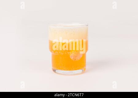 Orange Vitamin-C-Brausetabletten fallen gelassen und lösen sich in einem Glas Wasser mit Blasen auf weißem Hintergrund auf Stockfoto