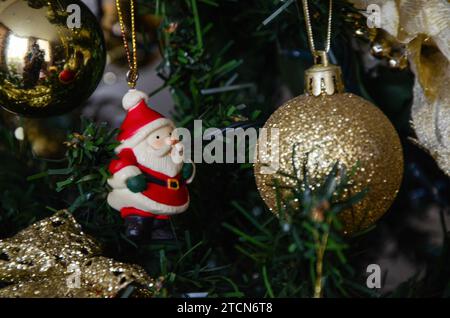 Der Weihnachtsmann mit roter Mütze, weißem Bart und Schnurrbart, schwarzem Gürtel, ziert den Weihnachtsbaum, hängt an einer goldenen Schnur, in der Mitte von zwei Kugeln Stockfoto