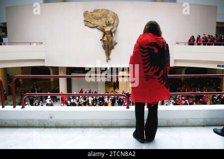 Tirana, Albanien - 28. November: Eine Frau, die mit einer albanischen Flagge gekleidet ist, steht vor der Statue von Mutter Teresa, inmitten einer feierlichen Menschenmenge Stockfoto
