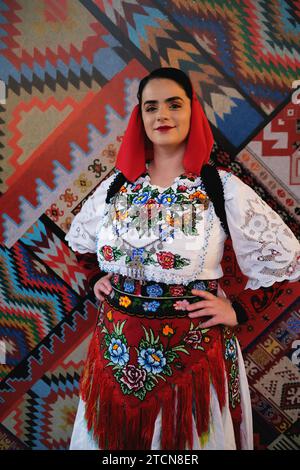 Tirana, Albanien - 28. November: Eine Frau in albanischer Kleidung posiert allein vor einem Hintergrund mit traditionellen albanischen Mustern Stockfoto