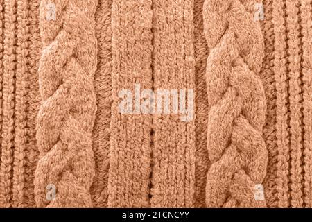 Gestrickte Textur mit Farbton des Jahres 2024 Pfirsichfarben, Wollgarn, kuscheliger, handgefertigter Winter-Herbst-Pullover Stockfoto