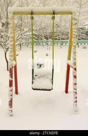 Kinderschaukel, bedeckt mit einer dicken Schneeschicht nach einem schweren Schneefall Stockfoto