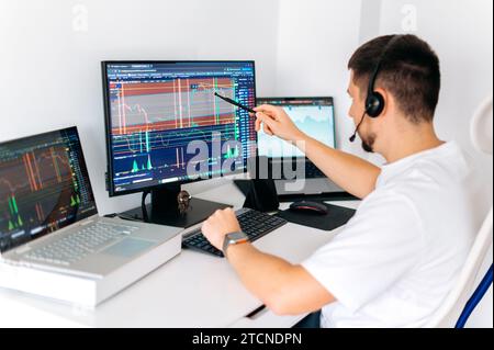 Online-Handel. Erfolgreicher männlicher Kryptohändler sitzt zu Hause an seinem Schreibtisch, handelt an der Börse, analysiert die Zukunft der Kryptowährung, bewertet Risiken, arbeitet online Stockfoto