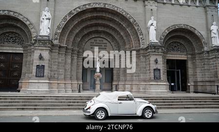 Ein Vorderblick auf eine Kirche in Intramuros, einer Stadt, die während der spanischen Kolonialisierung in Manila, Philippinen, entstand - mit einem weißen Auto davor. Stockfoto