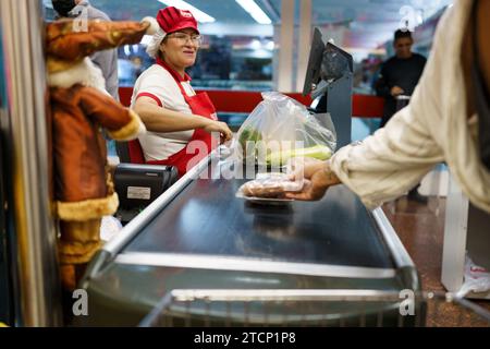 Caracas, Venezuela. Dezember 2023. Die Kassen in einem Supermarkt werden gesehen, als die Leute Lebensmittel einkaufen. Nach einem kurzen Boom dank der Dollarisierung der Wirtschaft ist Venezuelas wirtschaftliche Lage mit einer jährlichen Inflation von 398 % und einem Rückgang der Wirtschaftstätigkeit um 7 % immer noch beunruhigt. Mit einem Mindestlohn von nur 8 Dollar kämpft ein Großteil der Bevölkerung immer noch darum, das Ende des Monats zu erreichen. (Foto: Davide Bonaldo/SIPA USA) Credit: SIPA USA/Alamy Live News Stockfoto