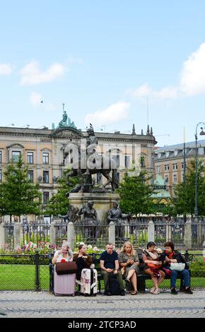 Tourist sitzt neben der königlichen Reiterstatue von Christian V. auf dem Kongens Nytorv / Königsneuplatz im Zentrum von Kopenhagen, Dänemark. Stockfoto