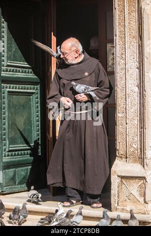 Mönch in Dubrovnik füttert die Tauben nahe dem Pfahltor Stockfoto