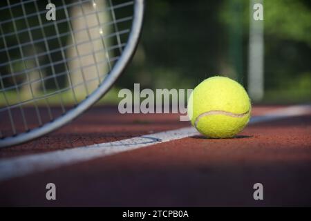 Low-Angle-View-Tennisszene mit gelbem Ball in der Nähe von Schläger und weißer Linie in einem Sport- und gesunden Lifestyle-Konzept Stockfoto