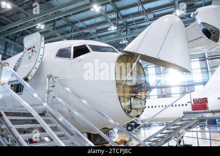 Frontansicht der in Wartung befindlichen weißen Passagierfluggesellschaften im Flugzeughangar. Der Jetliner hat das Wetterradar geöffnet. Mechanische Anlage prüfen Stockfoto