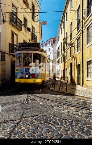 Flacher Blick auf eine Vintage-Straßenbahn, die durch eine enge Straße fährt, Alfama District Lissabon, Portugal Stockfoto