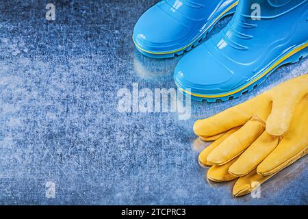 Wasserdichte Gummistiefel Ledersicherheitshandschuhe auf metallischem Hintergrund Gartenkonzept Stockfoto