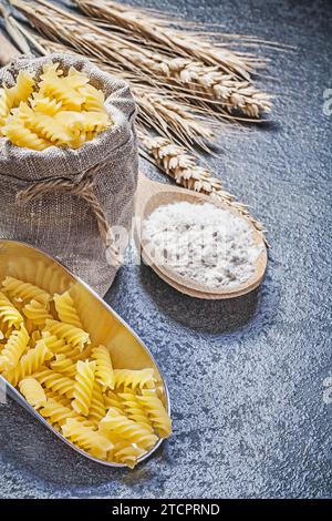 Hessische Sack Spirale Makkaroni Servierschaufel Holzlöffel Mehl Weizen Roggen Ohren auf schwarzem Hintergrund Stockfoto